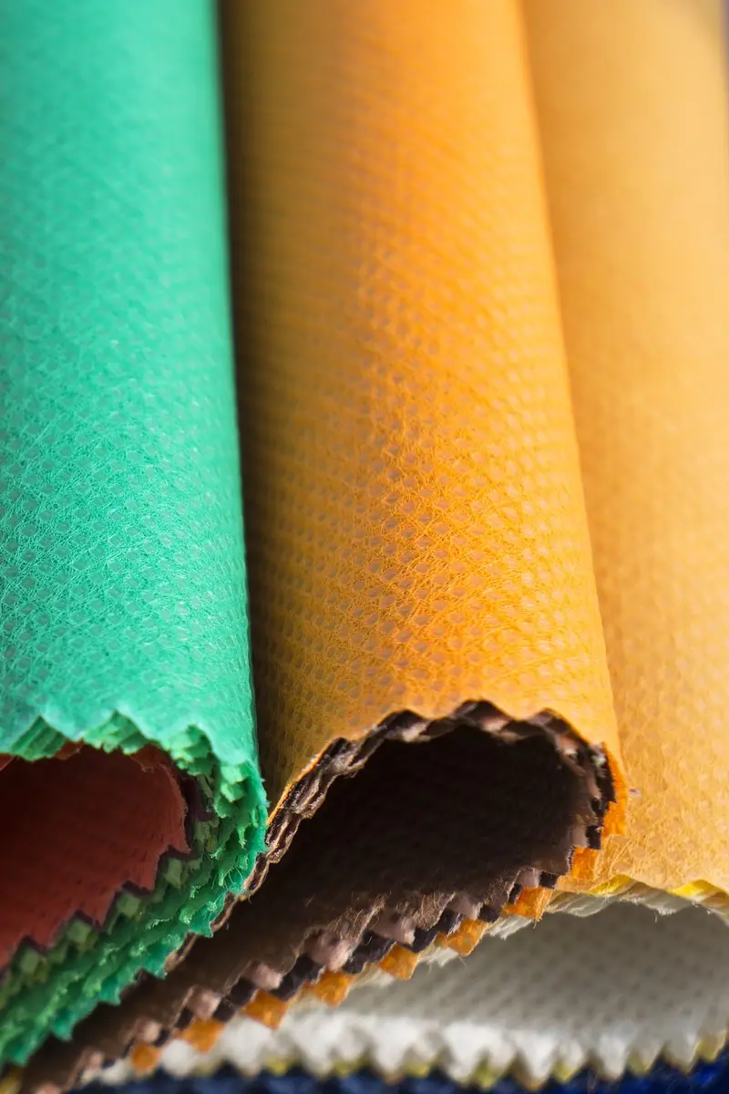 Folded fabric swatches in pink, red, green and orange fanned out on a table.