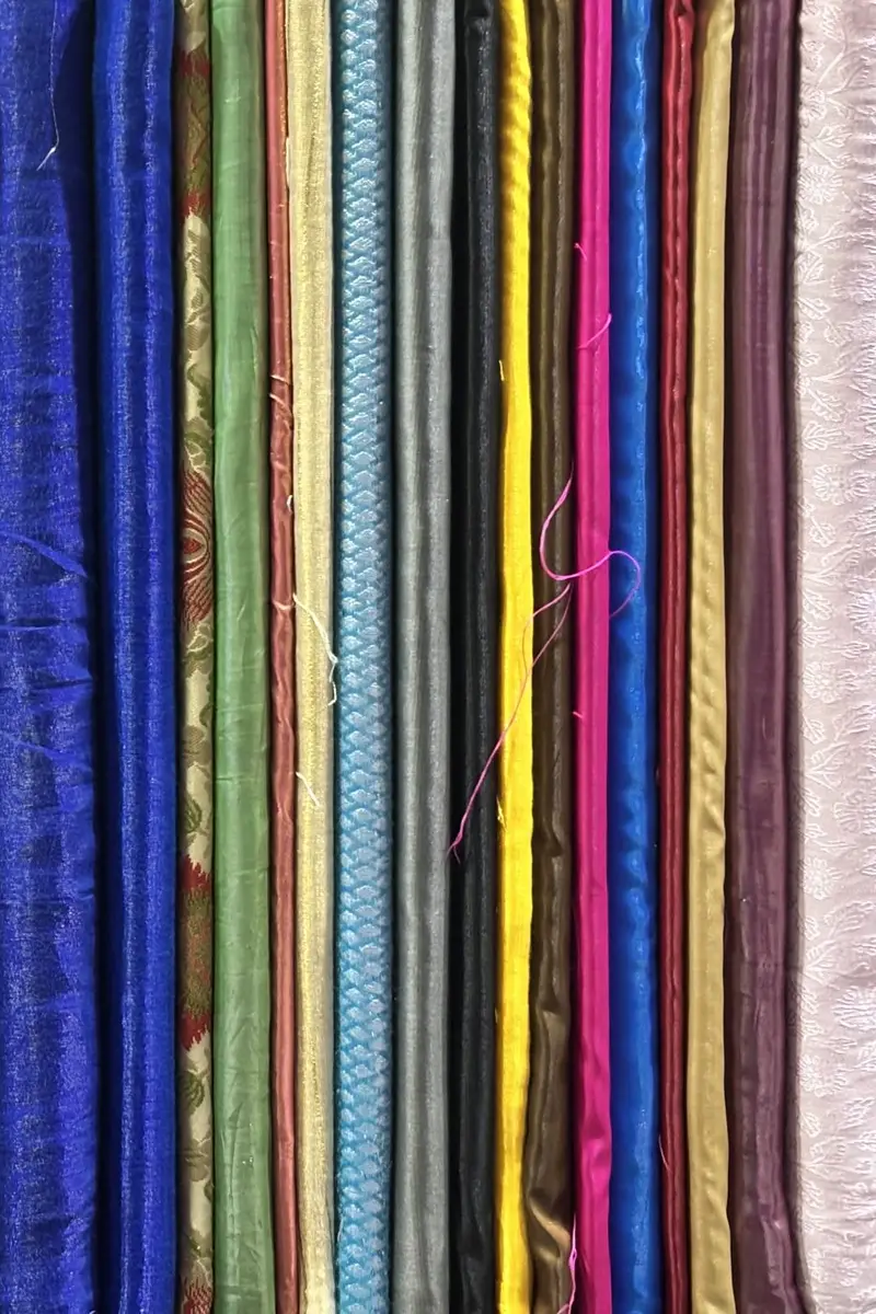 Rolls of fabric in many colours and weaves lined up side by side.