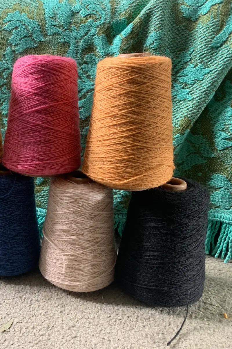 Cones of yarn in ten colours arranged in two rows.