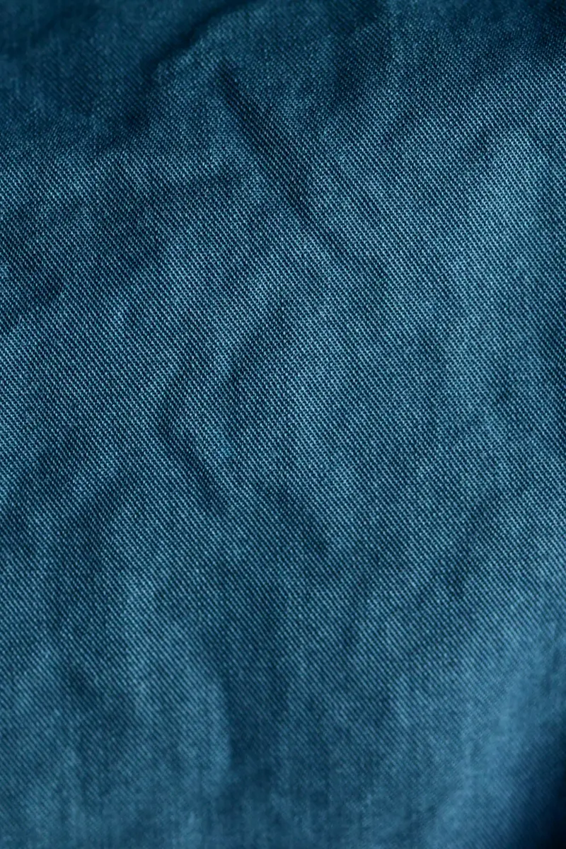 Close-up of crumpled plain blue cotton fabric showing the weave.