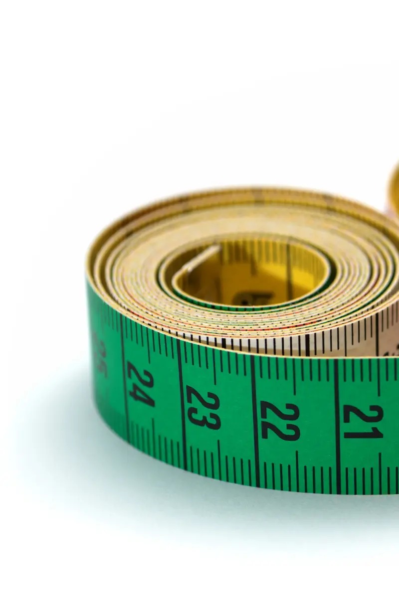 A coiled tailor's measuring tape in green, white, red and yellow on a white background.