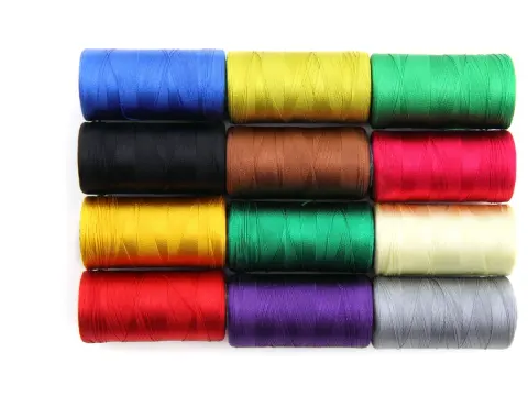 Twelve spools of glossy coloured polyester sewing thread laid out on a white background.