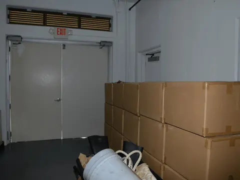 Plain brown cardboard cartons stacked in the corner of a warehouse room.