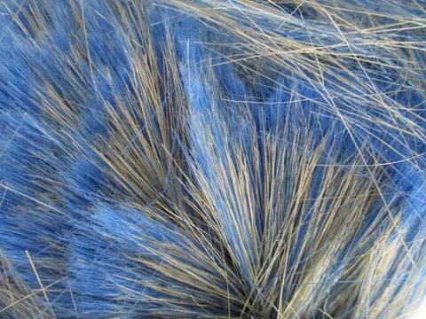 Close-up of loose blue polyester fibres mixed with fine natural bristles.